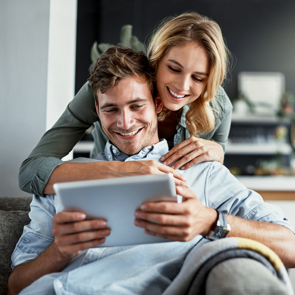Couple is smiling while looking at the tablet